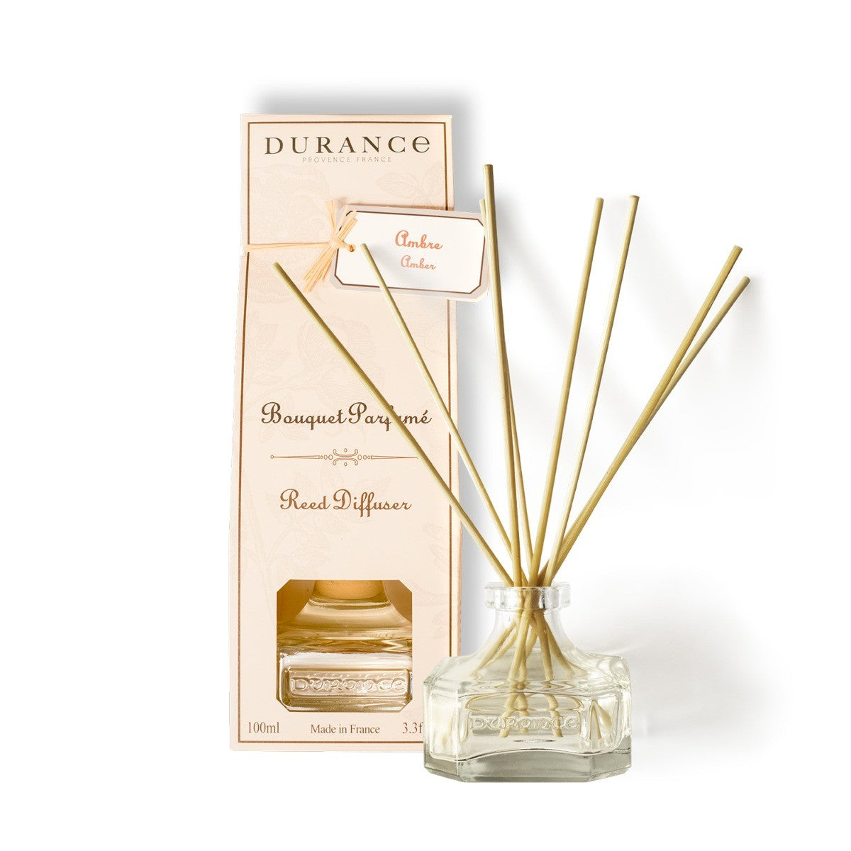 A Durance branded amber scented oil diffuser with a clear glass bottle and gold-colored amber oil, placed next to its packaging box.